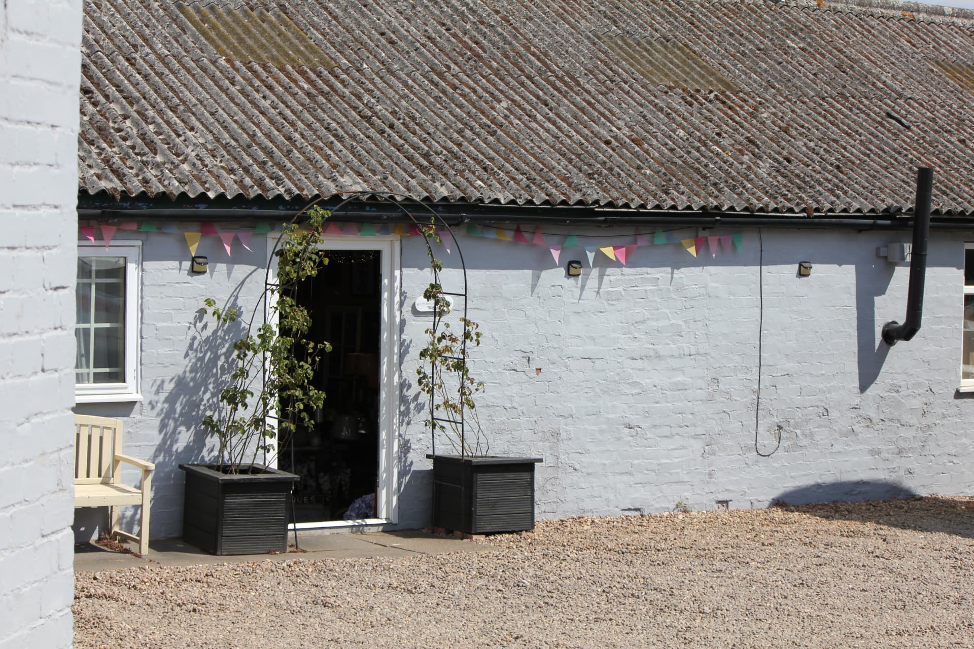 The whitewashed shop front with bunting and rose arch