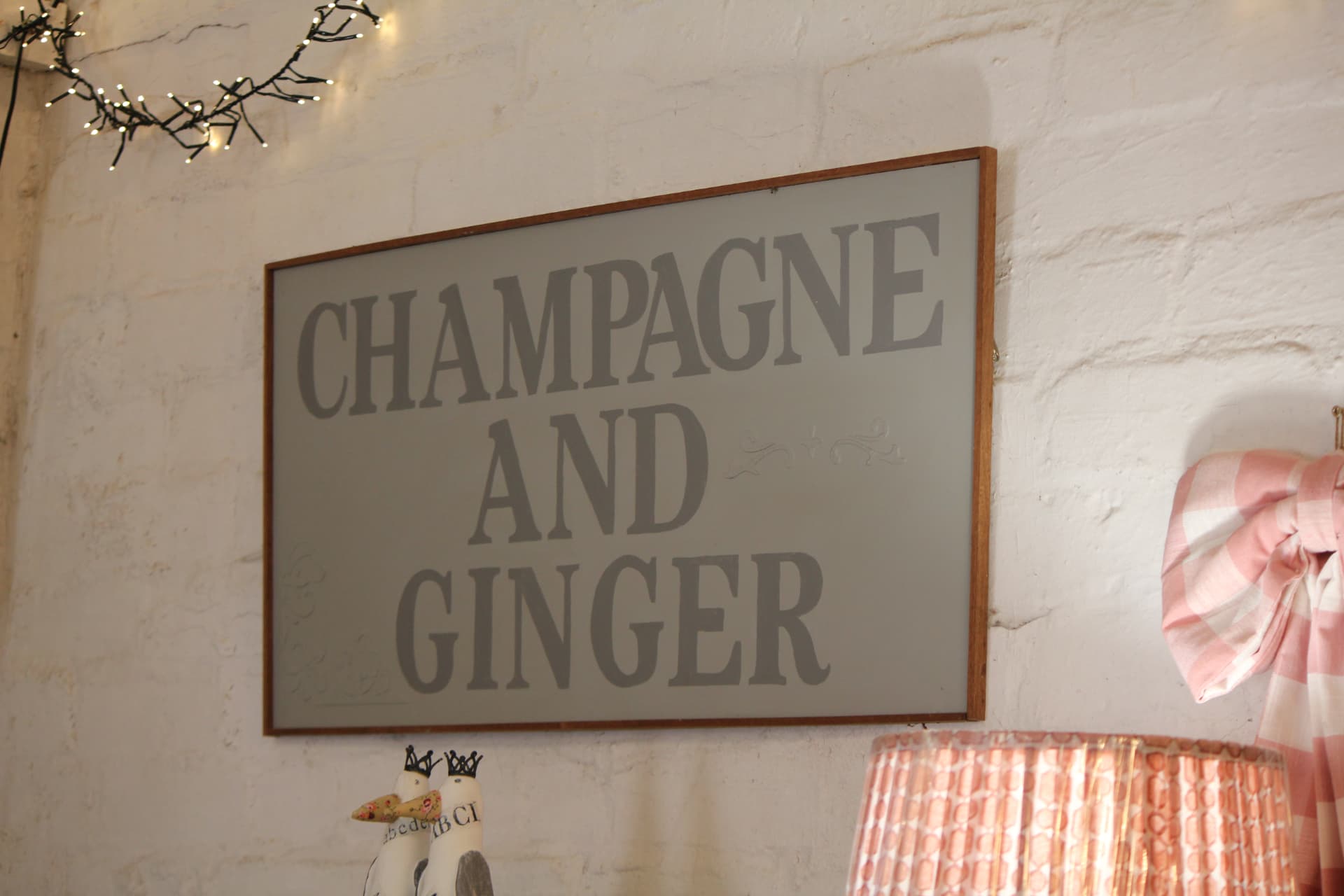 A framed Champagne & Ginger sign on the whitewashed wall