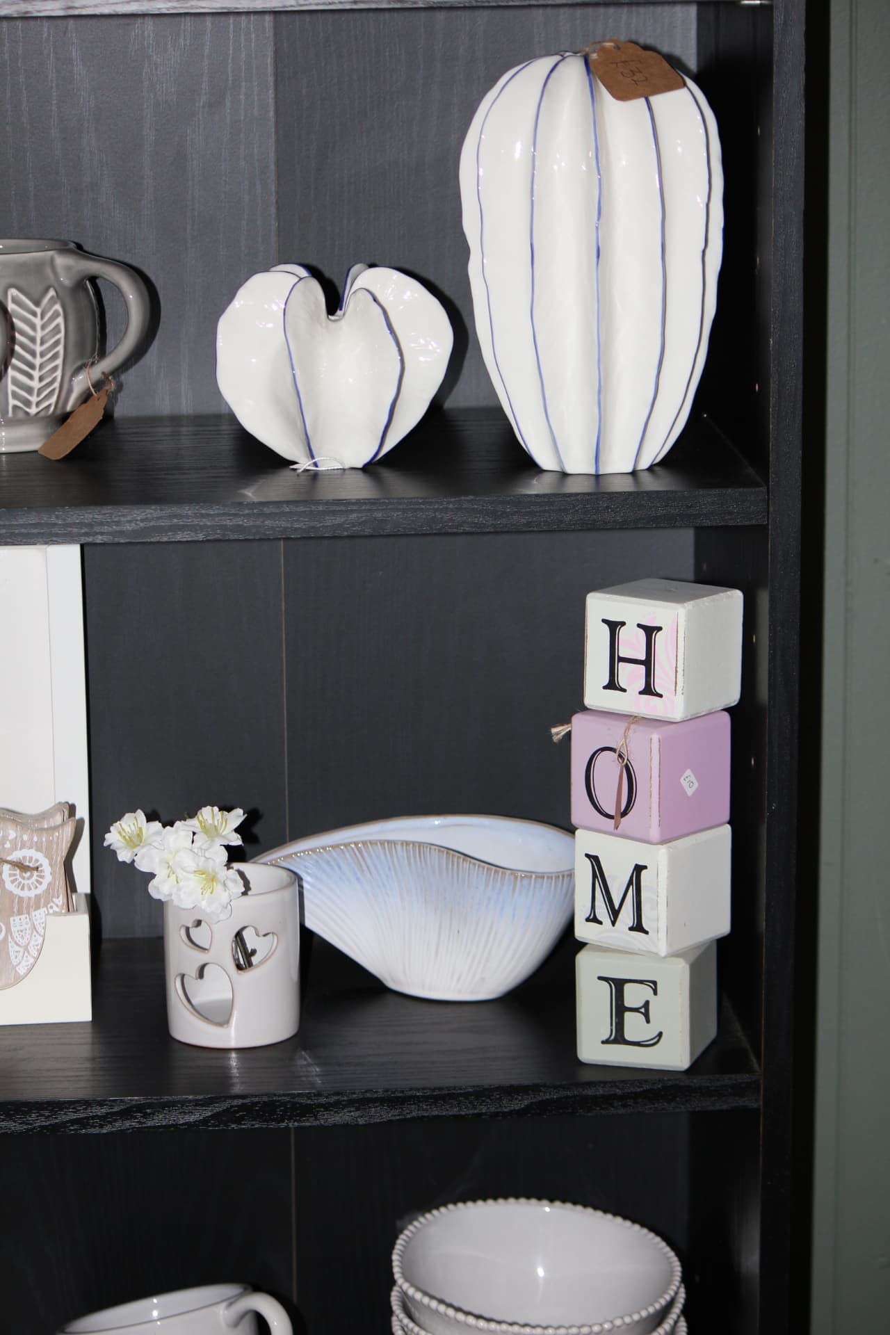 Contemporary white ceramics and HOME blocks on dark shelving