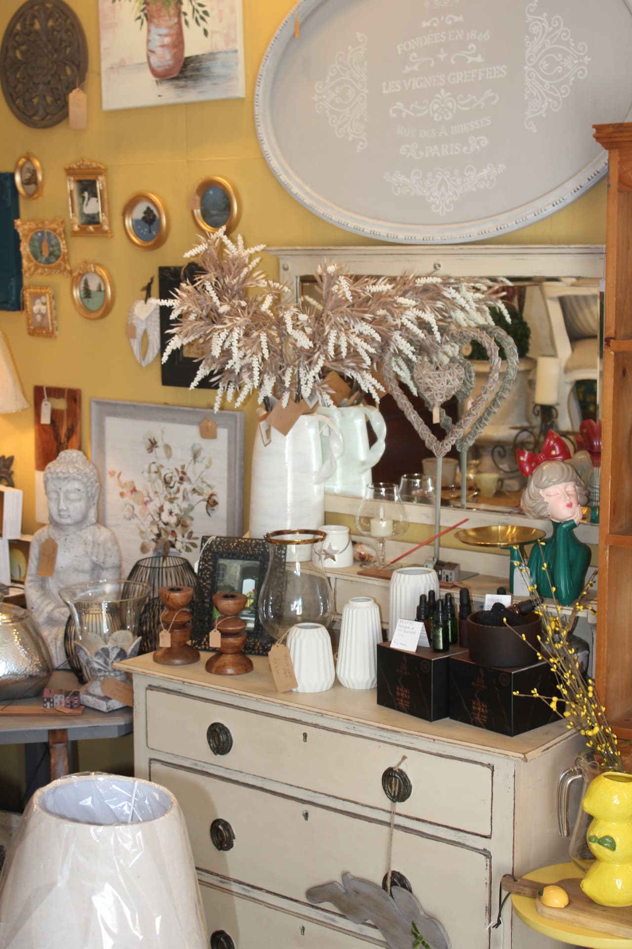 A painted dresser layered with vases, candles and artwork